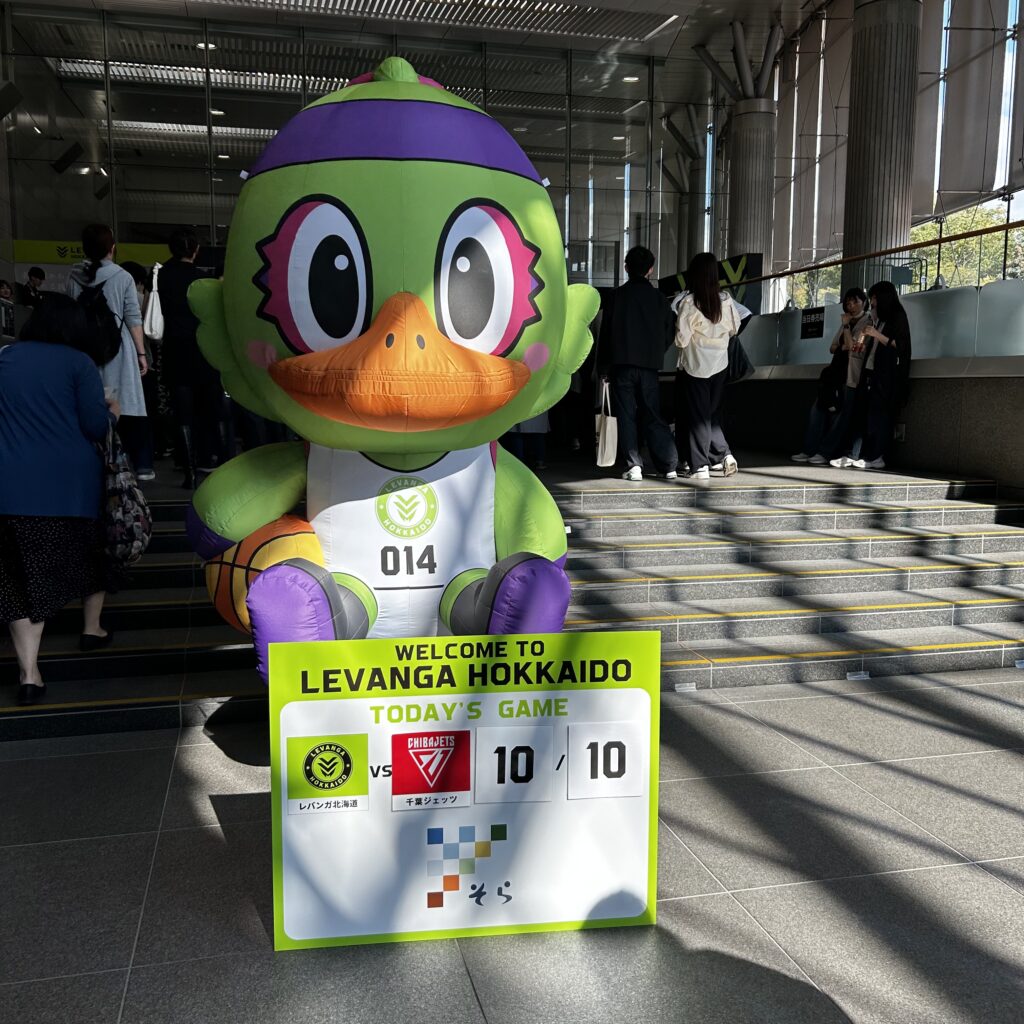 きたえーるの階段に置かれた緑色のマスコットと、10月10日のレバンガ北海道対千葉ジェッツの案内板